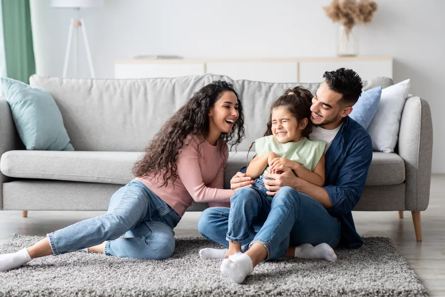 Parents laughing with their young daughter